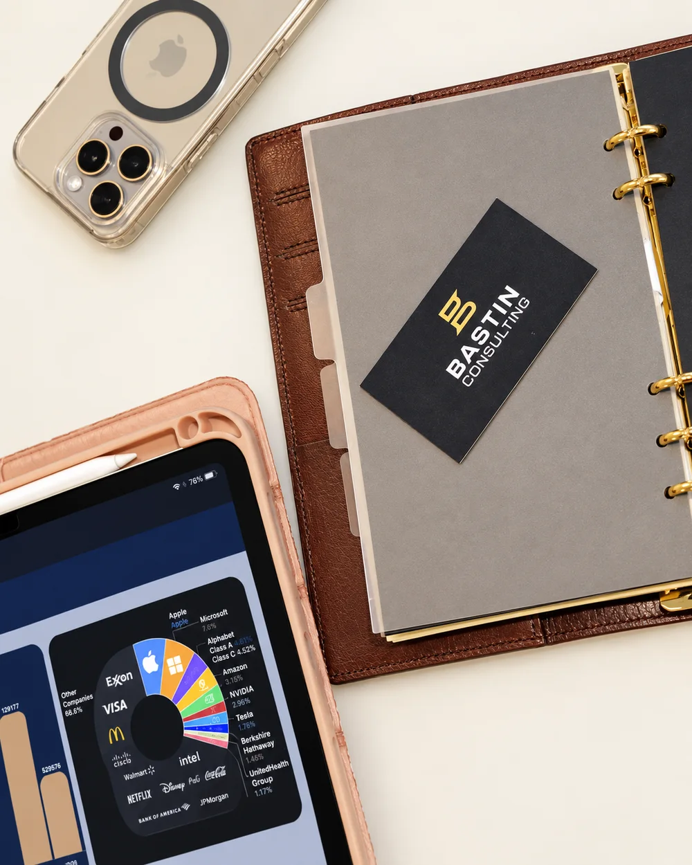 A tablet showing a portfolio breakdown beside a leather organiser and a Bastin Consulting card.